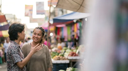 A warm interaction between a Filipino traveler and a local Filipino person engaged in friendly conversation in a casual setting.