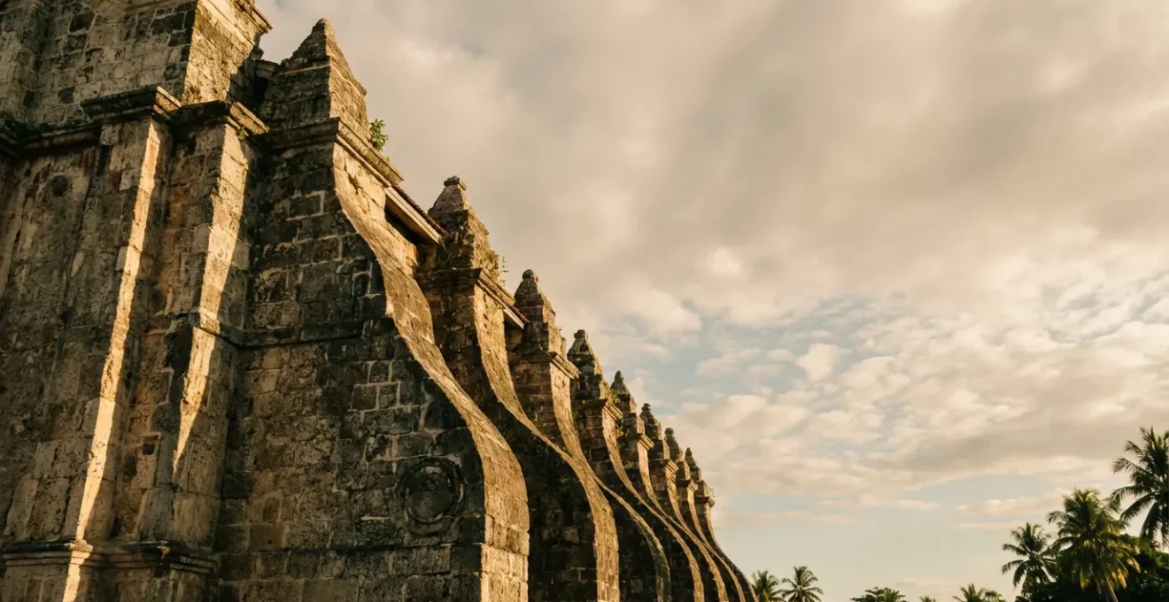 Massive stone buttresses supporting a historic Philippine Baroque church against dramatic sky
